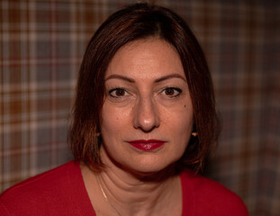 Caucasian mature female with red lipstick and short hair against plaid background