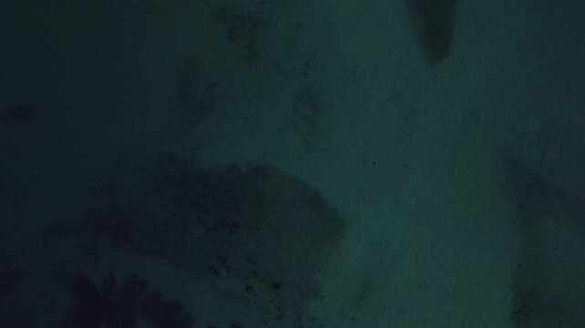Top-down drone view of the Sea of Cortez at sunset near El Tecolote Beach, revealing crystal-clear turquoise water, visible seabed, golden shoreline, and breathtaking coastal scenery bathed in warm ev