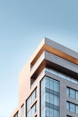 Obraz premium Modern architecture against a clear blue sky. Minimalist geometric building facade with glass windows. Concept for business, urban development, and real estate.