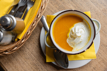 Rustic-style pumpkin cream soup served in a vintage metal bowl with chipped enamel and the word...