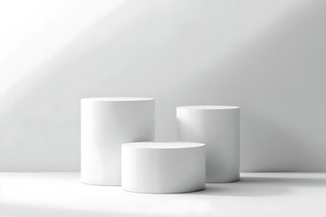 Three simple, white, cylindrical display stands arranged in a modern, minimalist setting against a light gray background