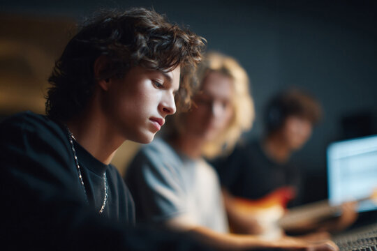 Creative teen working on music with friends in a home studio. Ideal for illustrating collaboration, youth culture, digital music production, and artistic endeavors.