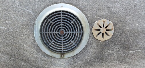 Round industrial air vent with radial grille mounted on a rough concrete wall. Functional urban...