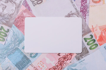 The white plastic card as a symbol of cashless payments on the background of cash paper money of...