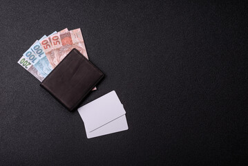 The white plastic card as a symbol of cashless payments on the background of cash paper money of...