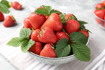Delicious ripe strawberries and green leaves on table, closeup