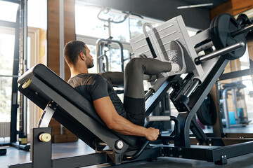 Fit man doing leg press exercise in modern gym. Focused on strength and lower body muscle building....