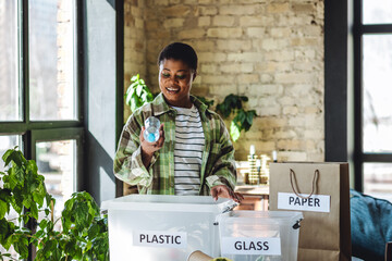 Young plus size African American woman doing waste sorting at home, care about planet, ecology....