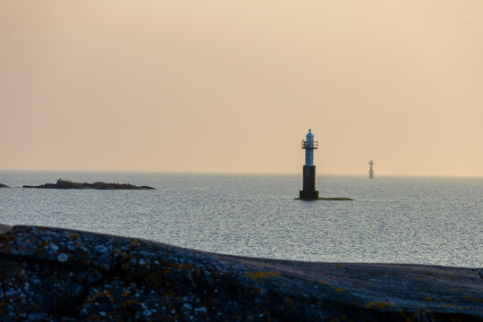 Two solitary lighthouses stand in calm waters under soft evening light. A serene seascape with Nordic minimalism and peaceful tones.