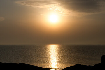 Sunset over open sea with golden reflections on the water. A calm, minimalist ocean scene with soft...