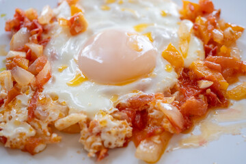 Fried egg with salsa or chopped vegetables on a white plate.