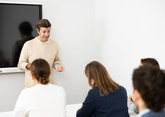 Male trainer near interactive board conducting advanced training courses to office employees...