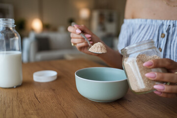 close up on female hands hold spoon with oat flakes and make breakfast