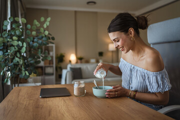 adult woman sit at table in the living room making healthy breakfast
