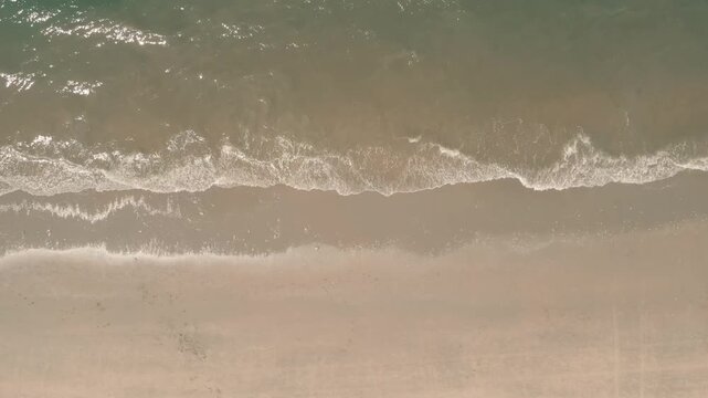 Aerial view of gentle waves meeting the sandy shore in a tranquil display of nature's rhythm captured from above, Zandvoort, North Holland, Netherlands.