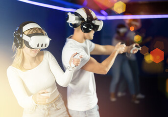 Young couple in VR glasses playing video game against another couple. Friends are enthusiastically...