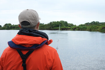 Back of Mature man fishing from the boat on the river