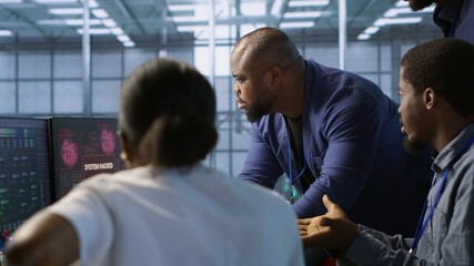 Obraz premium Cybersecurity specialists in server room trying to protect equipment from hacker stealing data. Programmers in data center office doing teamwork to delete virus attacking company servers, camera A