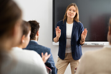 Experienced female teacher giving lecture to group of student