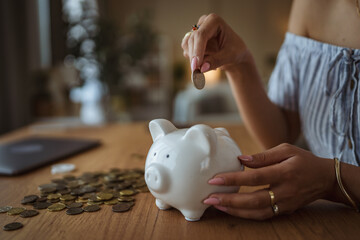 close up on female hand with coins and piggy bank