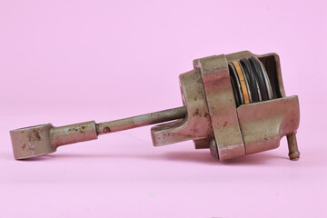 Turbocharger Actuator also known as a wastegate actuator with body cover partialy split and showing the inside part. isolated on pink background.