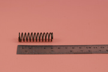 A spring compression and ruler with various sizes and lenghts Isolated on pink background.