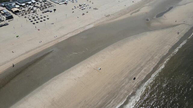 Aerial view of sun-soaked beach with beach umbrellas, restaurants, and people enjoying a sunny day, Zandvoort, North Holland, Netherlands.