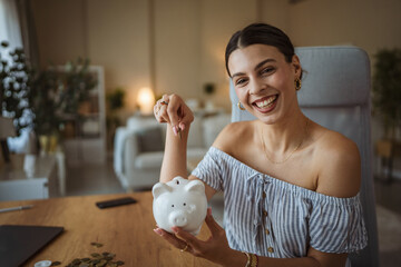 Portrait of excited happy adult woman puts coins in a piggy bank