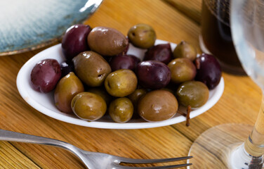 Large black and green olives on a white plate. Natural Italian olives from the farm for salad