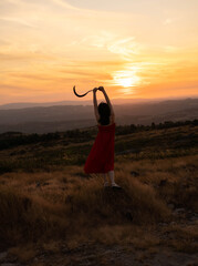 Dos mujeres en silueta se enfrentan en una colina durante un vibrante atardecer. Una de ellas, con...