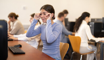 Young woman with tired eyes from working at computer in coworking space