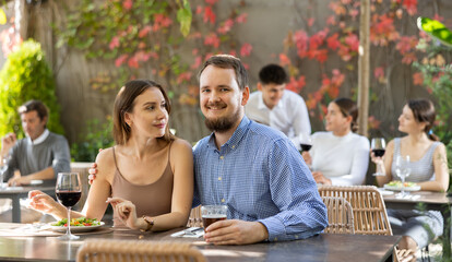 Portrait of loving couple with glasses of wine at a table in an open-air restaurant