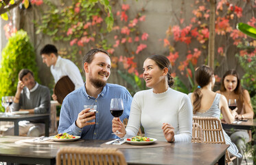 Loving couple drinking wine and talking while sitting at a table in an open-air restaurant