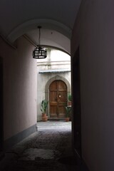 Hidden European courtyard with arched wooden door and potted plants, Bergamo, Italy