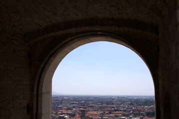 Fototapeta premium Ancient stone arch framing panoramic view of The Venetian Walls, Upper City, Bergamo rooftops, Italy
