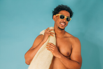 smiling young man wearing sunglasses in swim trunks isolated on white background with a beach or...
