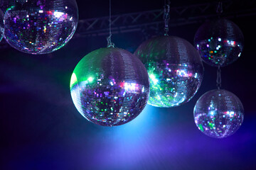 Composición de 5 bolas de espejos brillando con luces de tonos azules y verdes en un ambiente de...
