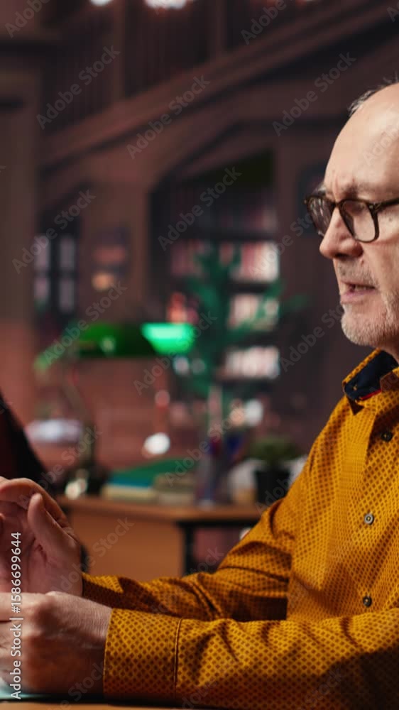 Poster vertical video aged man in a study area surrounded by library books and paperwork, preparing for uni