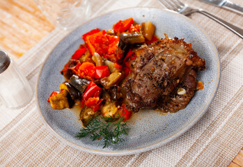 Baked pork cheek is seasoned with spices and garlic. Meat is complemented with stewed vegetables and sprig of dill.