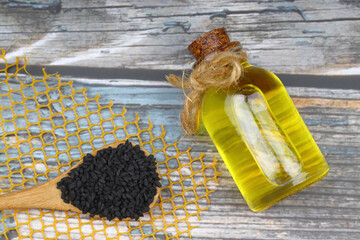 Black cumin seeds and essential oil with bowl and wooden shovel or spoon. Nigella Sativa in glass...