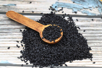 Black cumin seeds and essential oil with bowl and wooden shovel or spoon. Nigella Sativa in glass bottle. Organic herbal medicine for many diseases