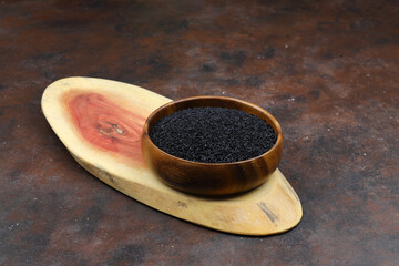 Black cumin seeds and essential oil with bowl and wooden shovel or spoon. Nigella Sativa in glass...