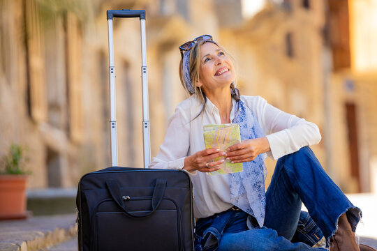 adult woman traveling sitting with map and suitcase