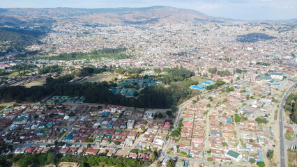 Aerial view of a densely populated city with buildings and trees against a mountain backdrop in daylight tanzania