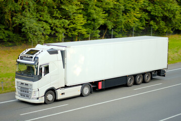 Modern Sustainable White Cargo Semi Truck with Box Trailer Driving on Forest Highway