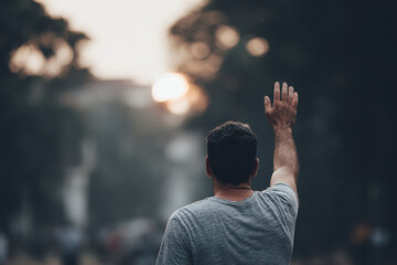 solitary person raises their hand in familiar greeting gesture signaling warmth and connection