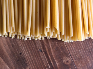 A Pile of Dry Bucatini Pasta with Ends Showing on a Rustic Wooden Surface
