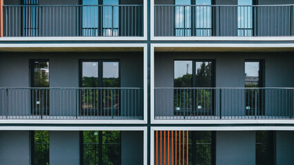 Modern apartment building facade with symmetrical balconies and dark tones