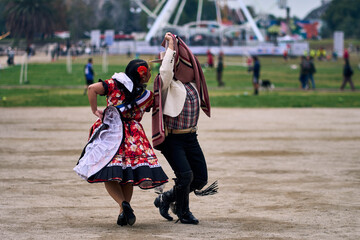 Portrait of a smiling young couple dressed as Chilean huasos, posing and joyfully dancing cueca...