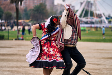 Portrait of a smiling young couple dressed as Chilean huasos, posing and joyfully dancing cueca...
